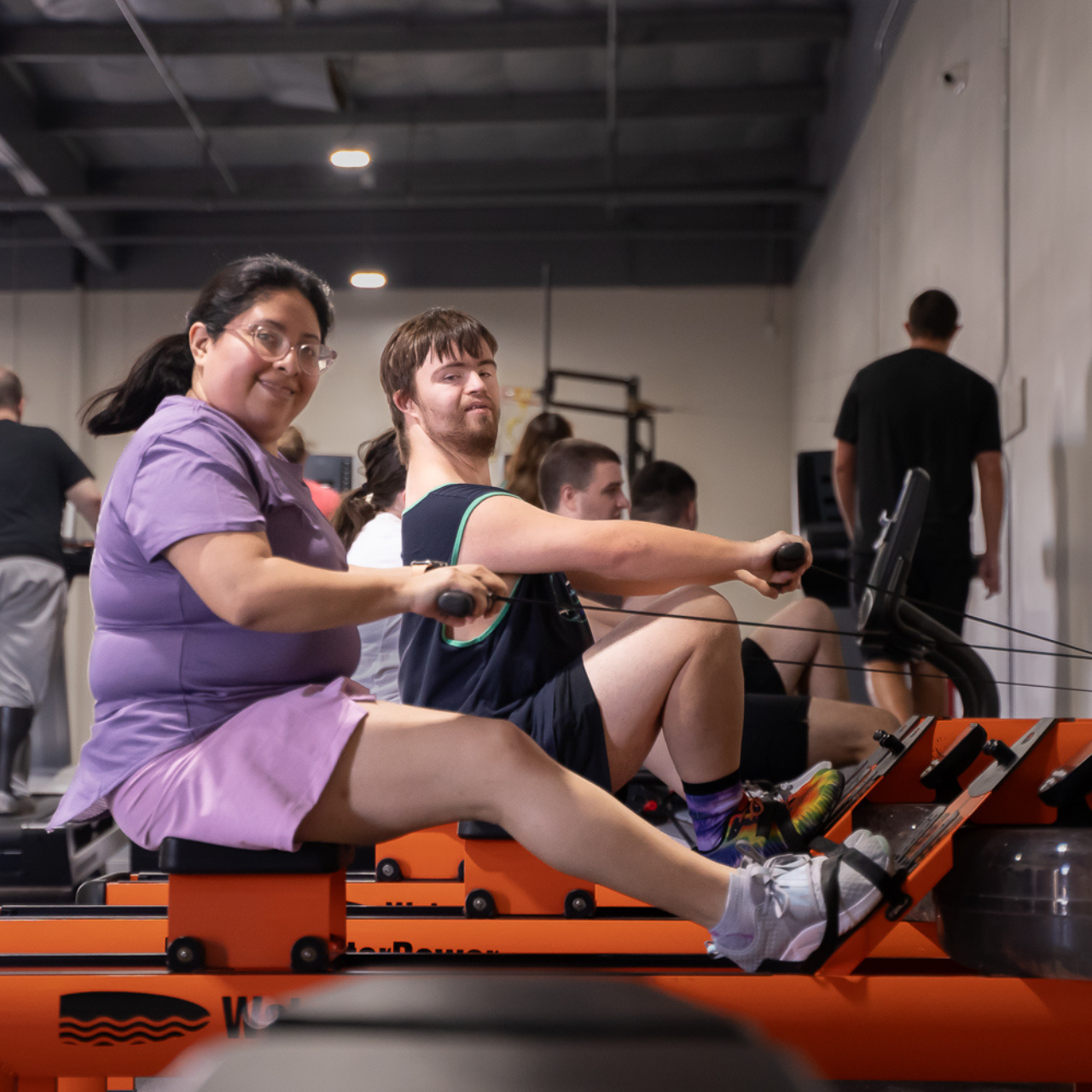 A group of people are rowing in a gym