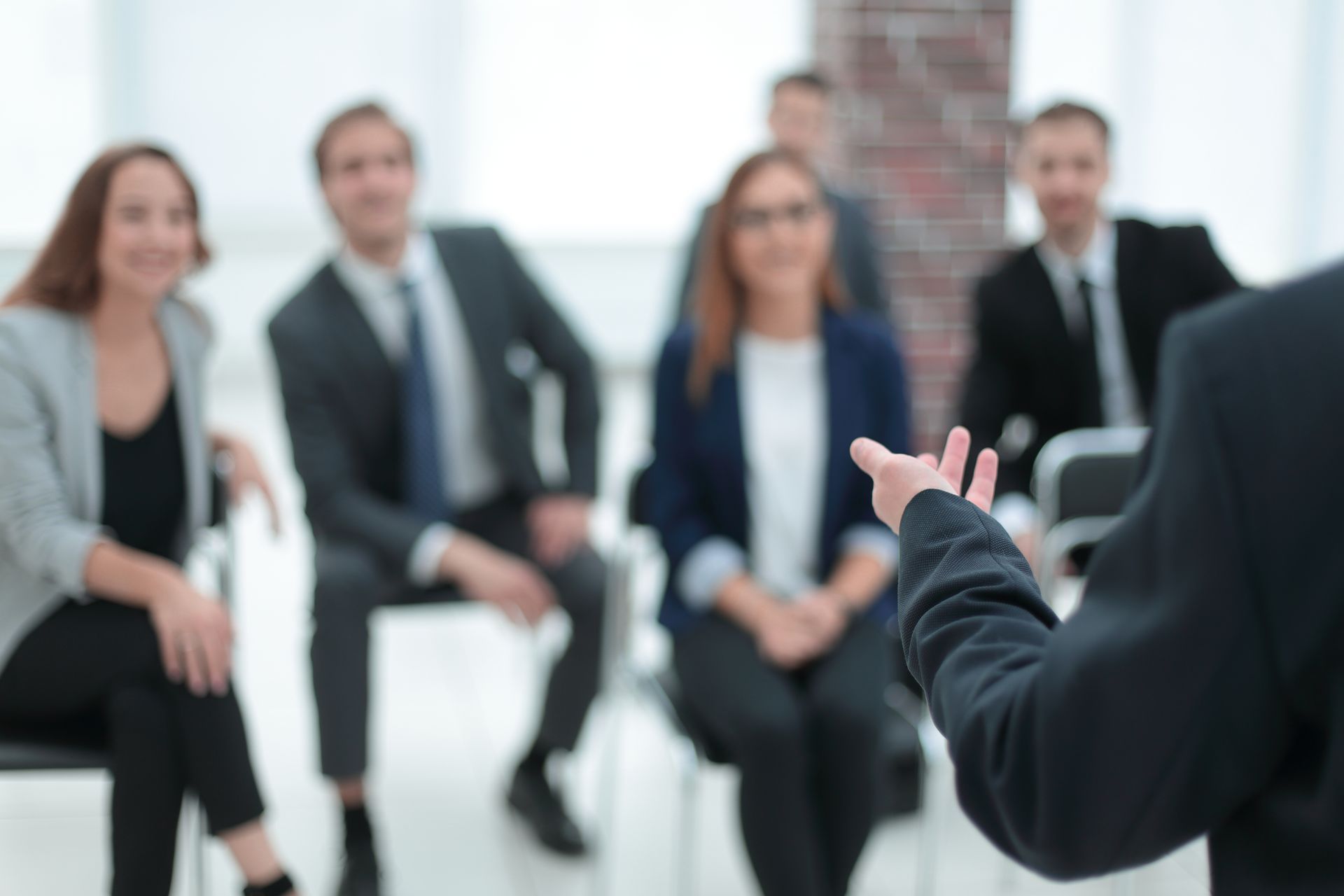 Job interview panel with a candidate speaking to three seated interviewers in a bright office