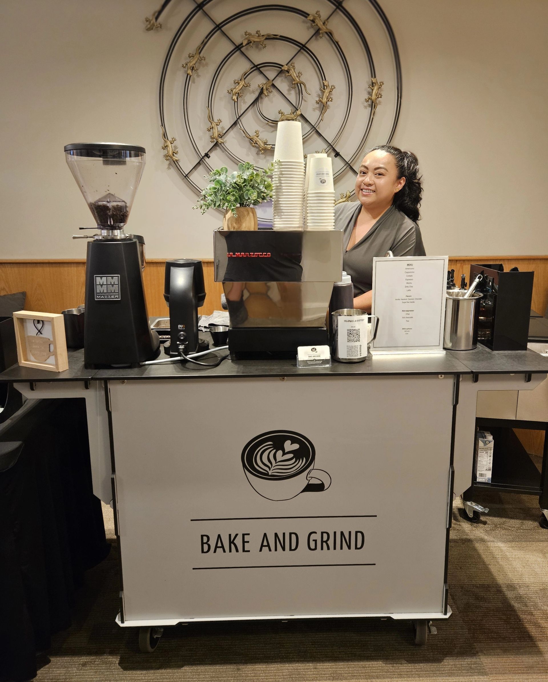 Coffee stand with a smiling vendor behind a counter labeled “Bake and Grind”