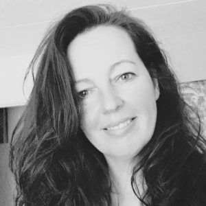 Zwart-wit portret van een lachende vrouw met lang donker haar.