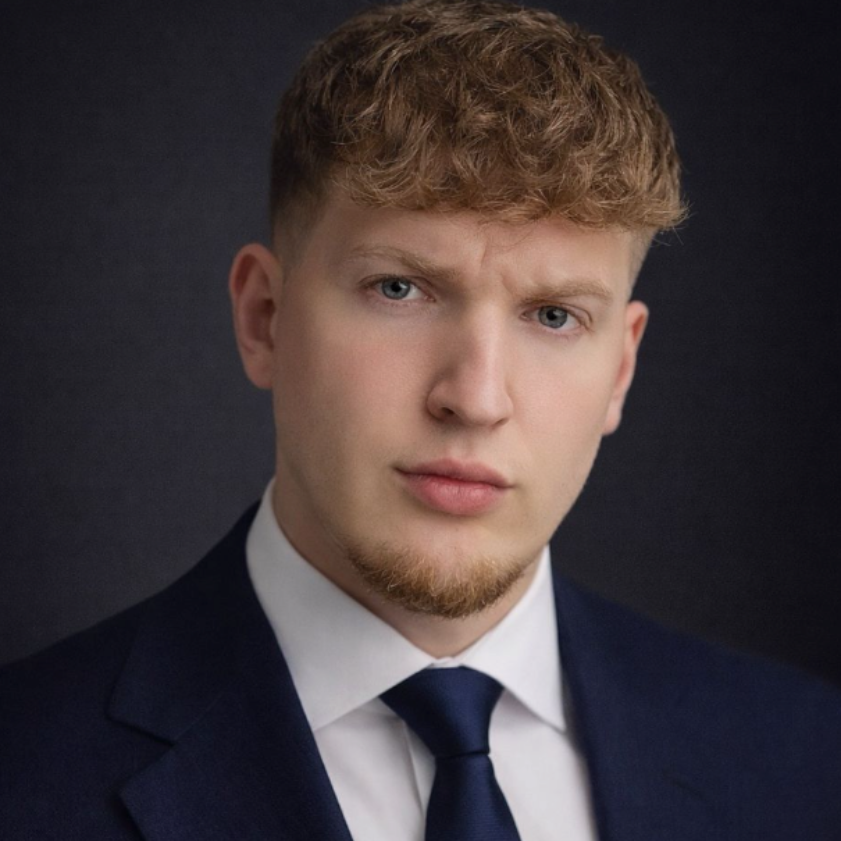 Studioportret van een man in een donkerblauw pak met stropdas tegen een donkere achtergrond.