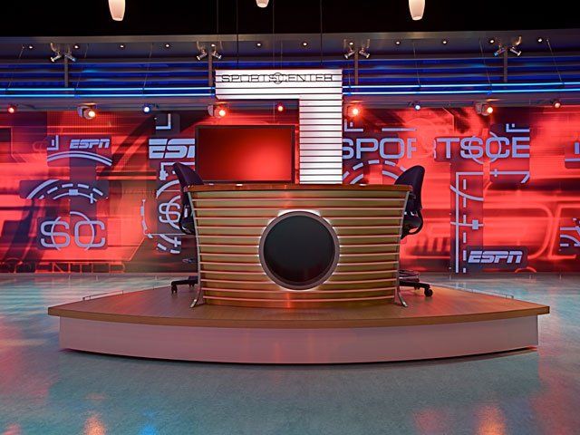 An espn studio with a wooden desk and chairs