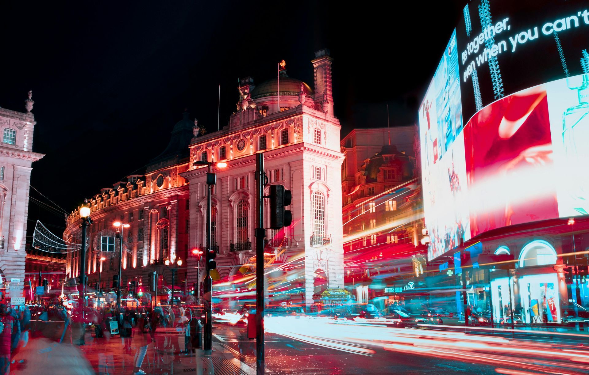 A city street at night with a large billboard in the middle of it.