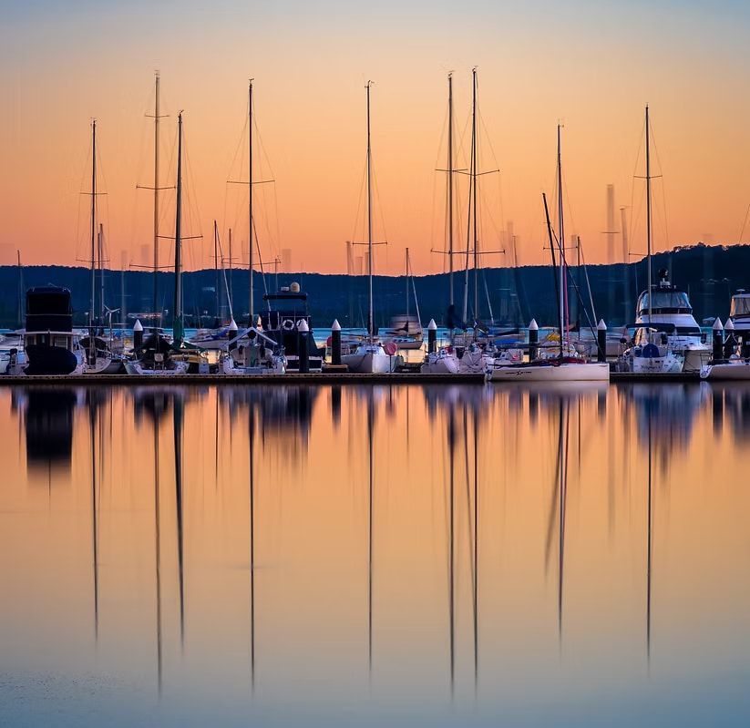 A Row of Boats Are Docked in a Harbor at Sunset — Gosford Sailing Club in Gosford, NSW