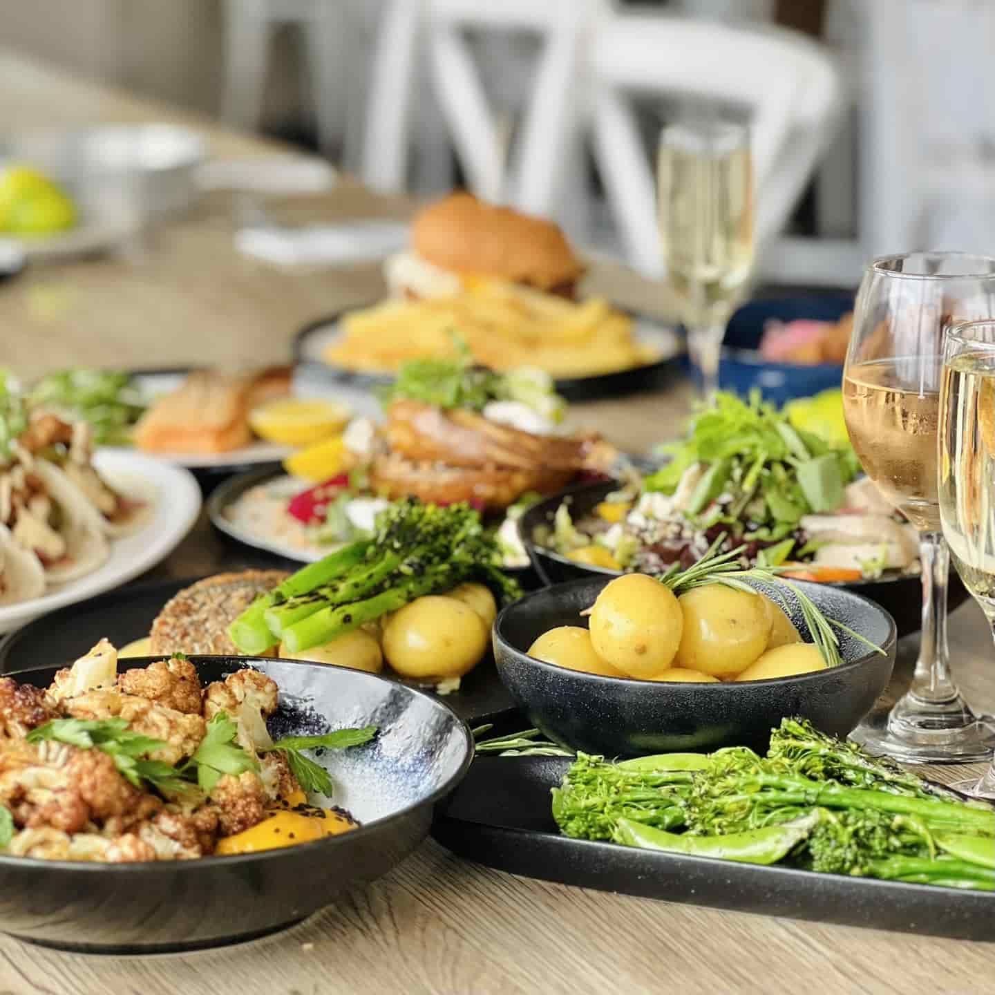A Table Topped With Plates of Food and Glasses of Wine — Gosford Sailing Club in Gosford, NSW
