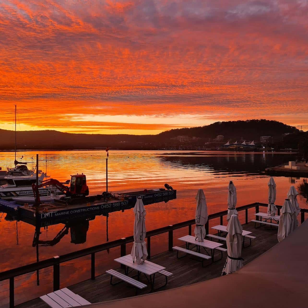 A Sunset Over a Body of Water With Tables and Umbrellas — Gosford Sailing Club in Gosford, NSW