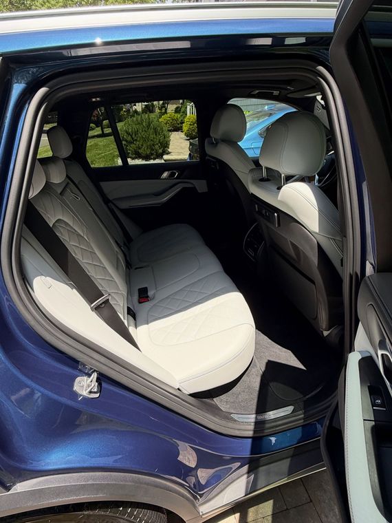 Blue SUV with rear door open, showing a white rear seat cover inside the back seat.