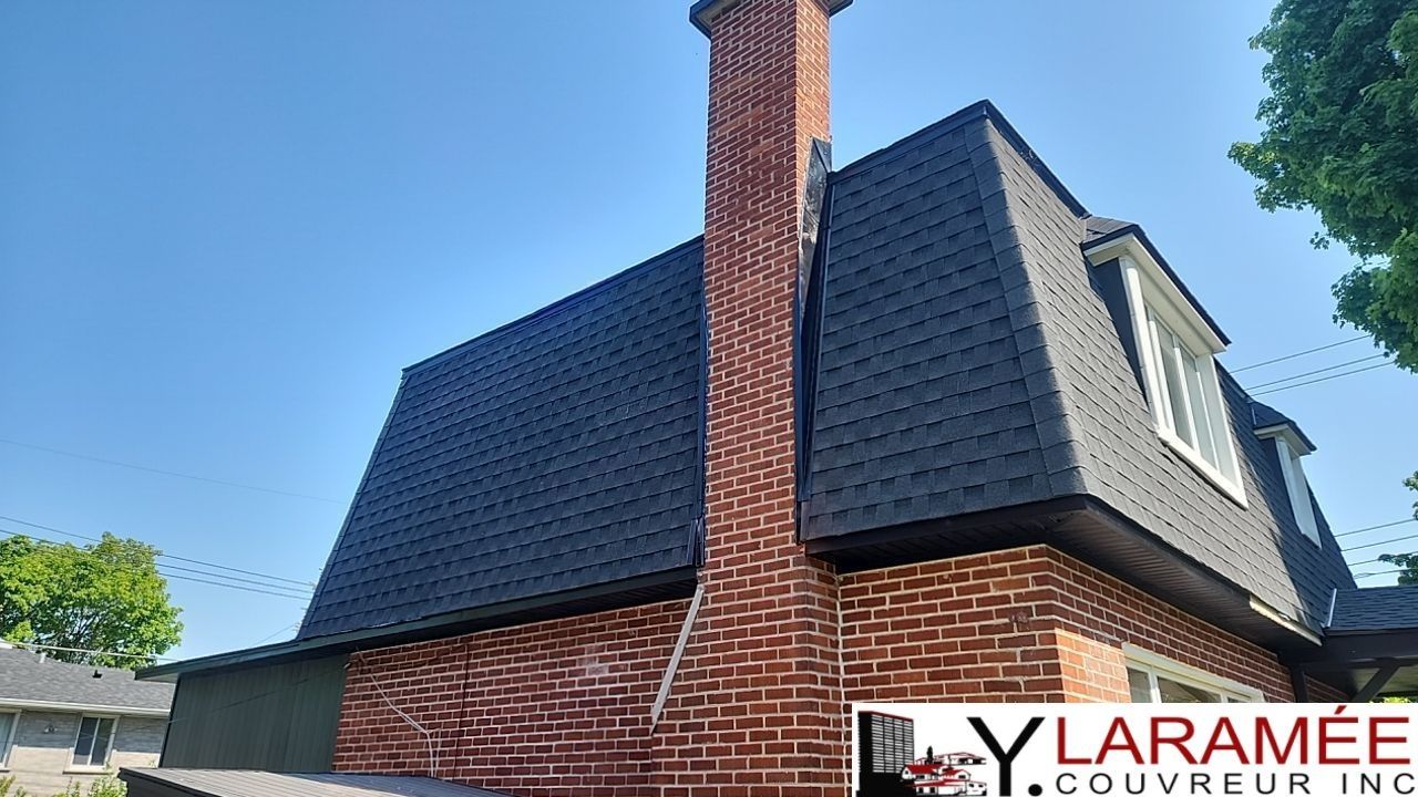 Une maison en brique avec un toit noir et une cheminée