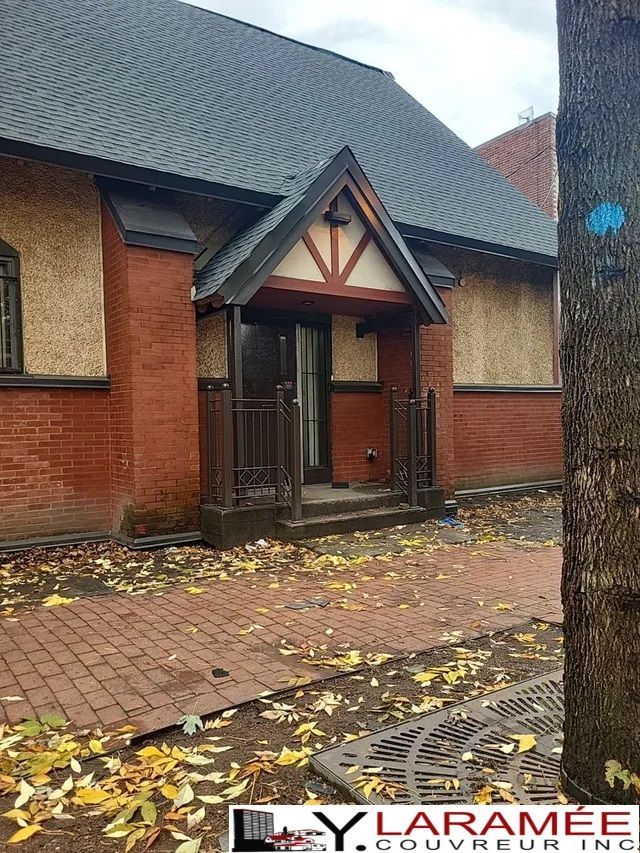 Un bâtiment en briques avec un porche et un arbre devant.