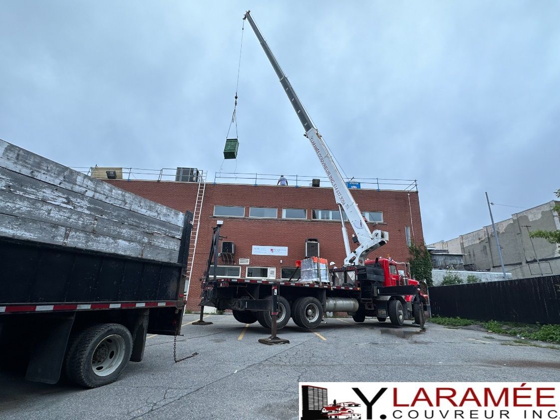 Un camion avec une grue dessus est garé devant un bâtiment.