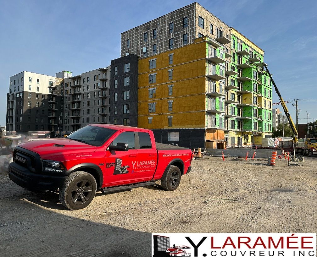 Un camion rouge est garé devant un bâtiment en construction
