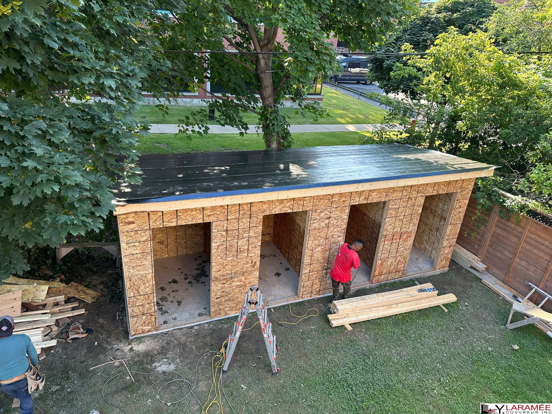 Un homme travaille sur un hangar en bois dans une cour arrière.