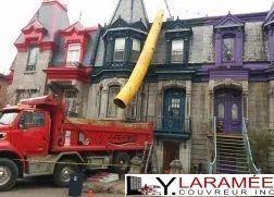 Un camion-benne rouge est garé devant une rangée de maisons.