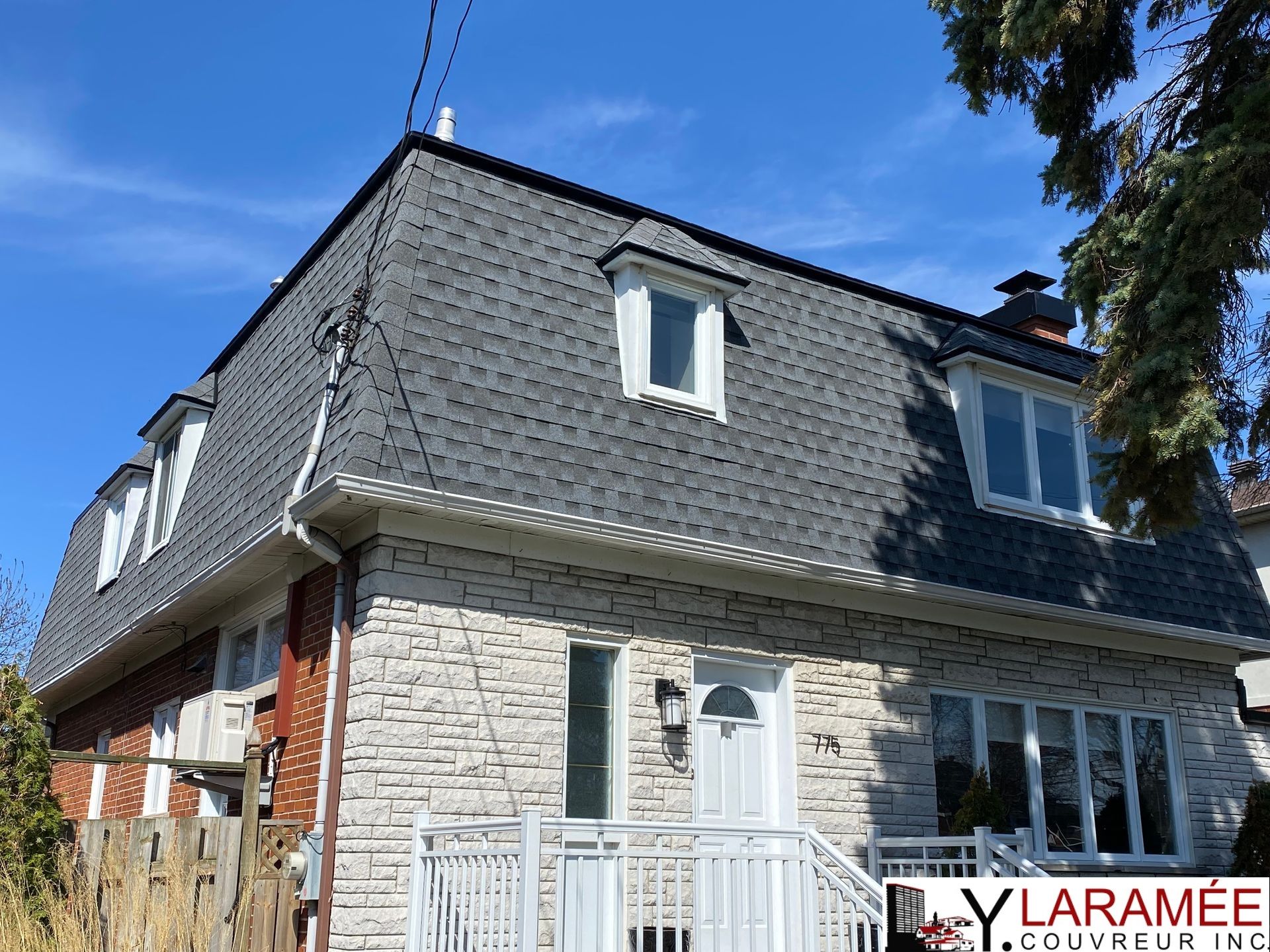 Une grande maison en briques avec un toit gris et des fenêtres blanches