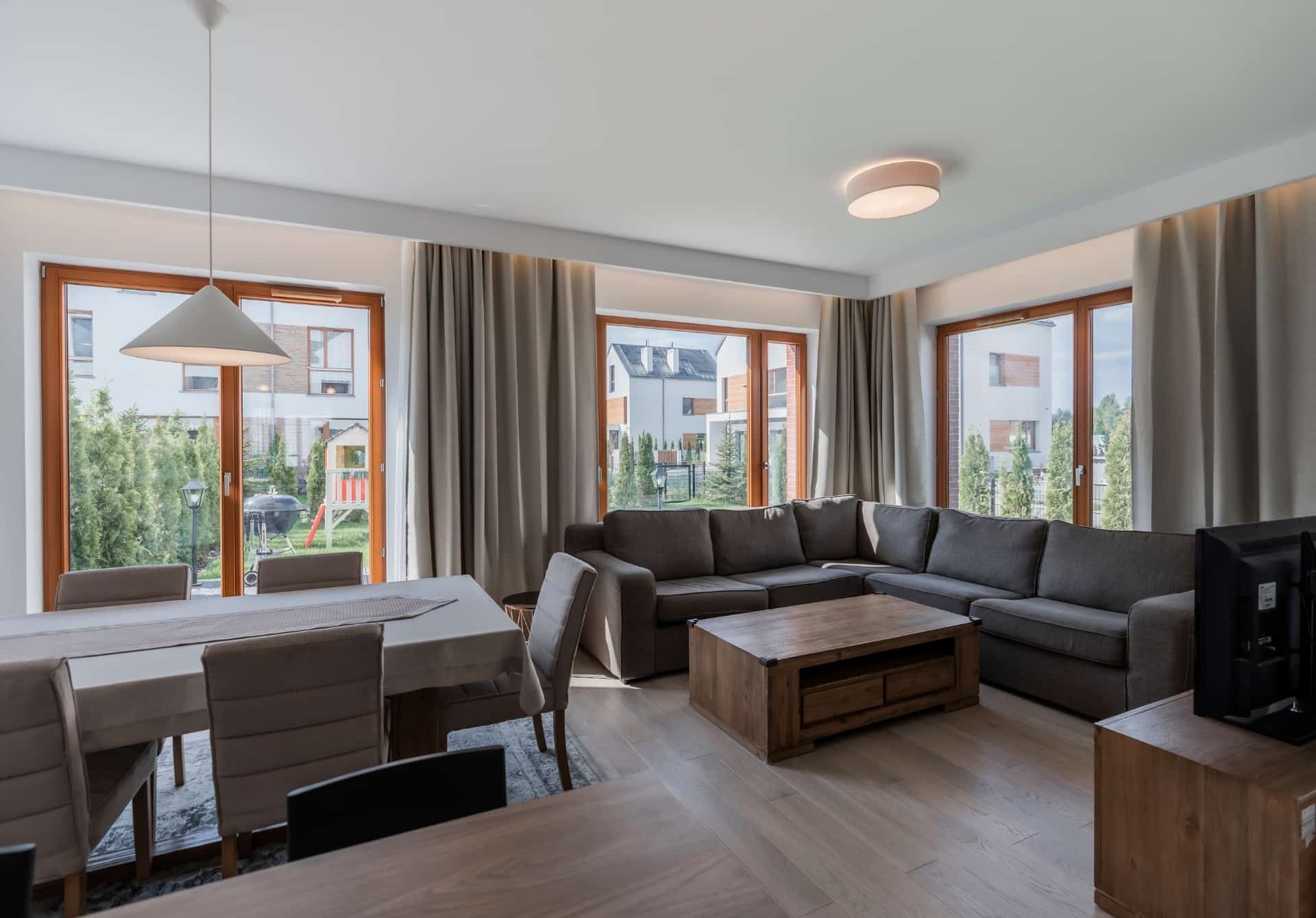 A living room with a large sectional couch , dining table , chairs and a coffee table.