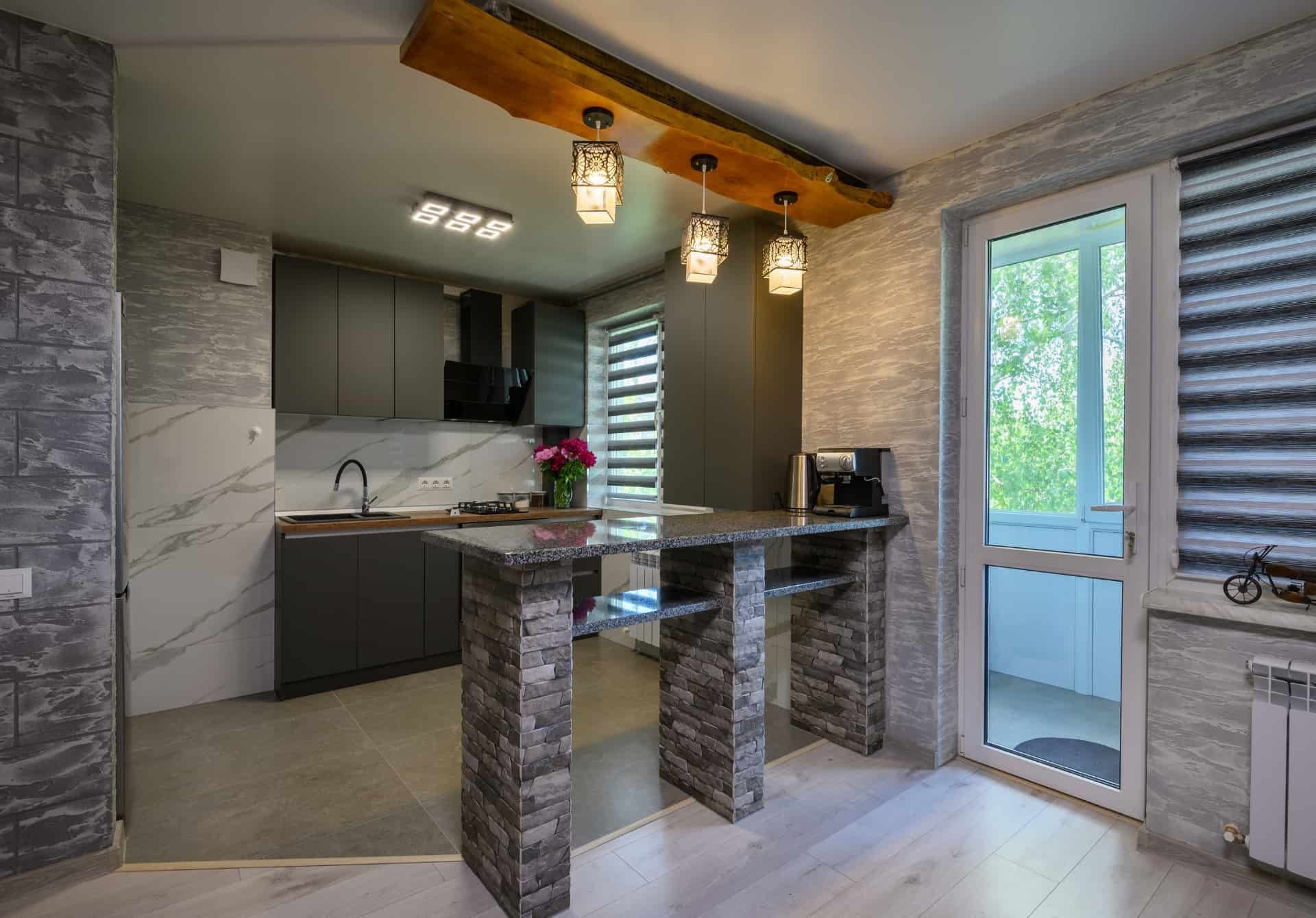A kitchen with a marble counter top and a wooden beam hanging from the ceiling.
