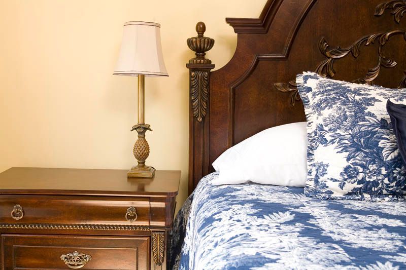 A nightstand next to a bed with a lamp on it