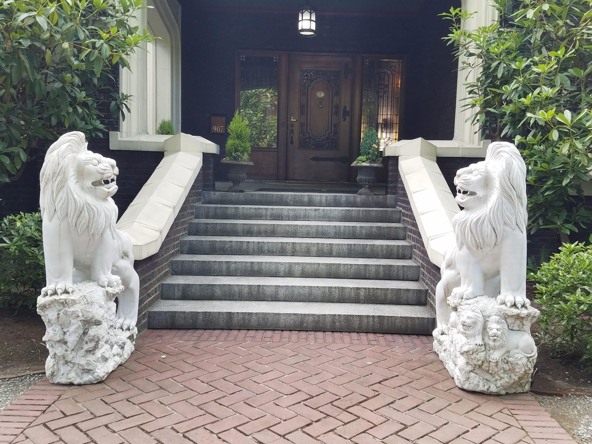 There are two statues of lions in front of a house.