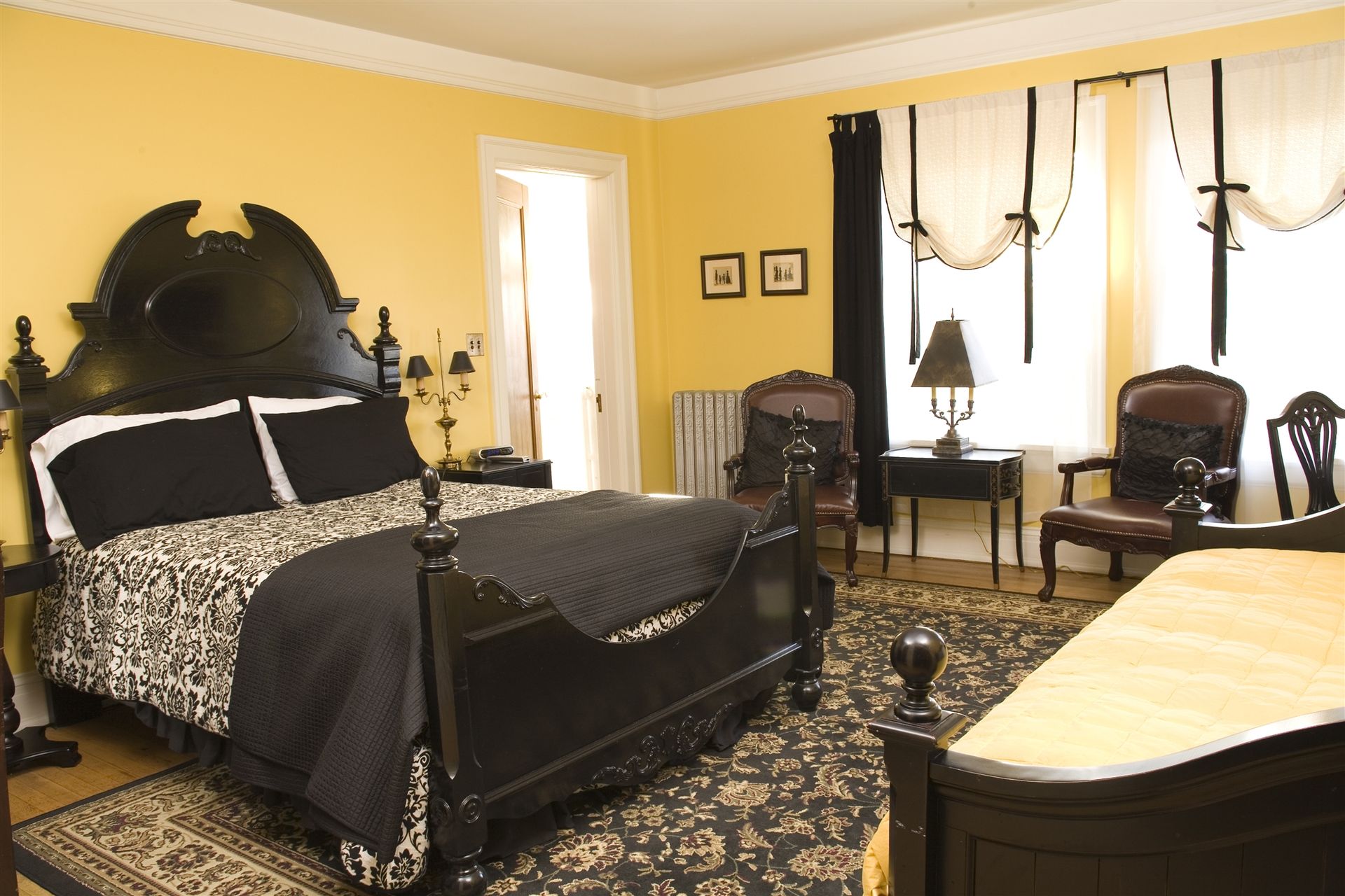 A bedroom with a black bed and yellow walls