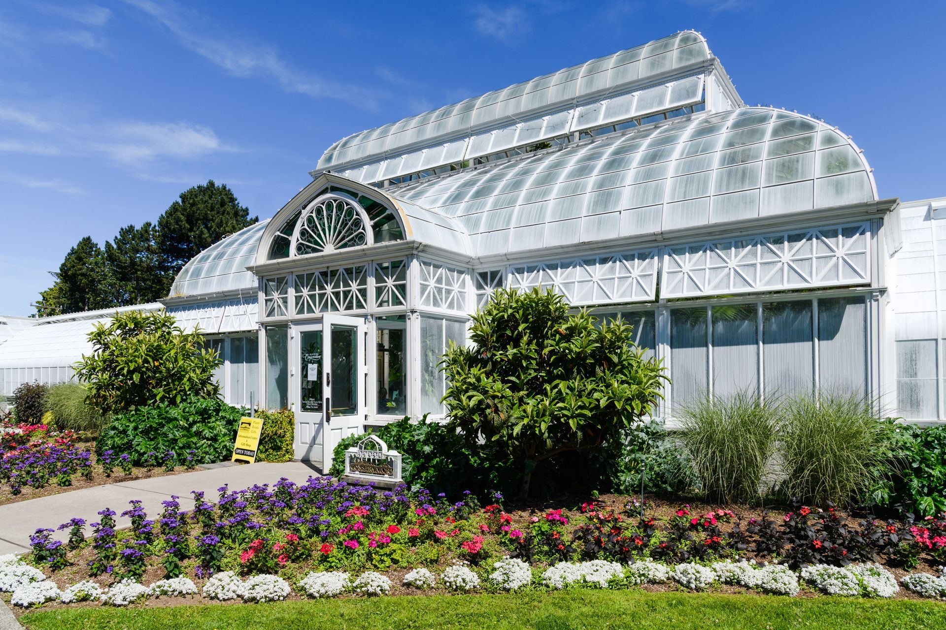 A large greenhouse with a lot of windows and flowers in front of it.