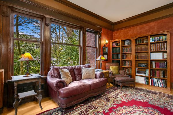 A living room with a couch , chairs , bookshelves and a rug.