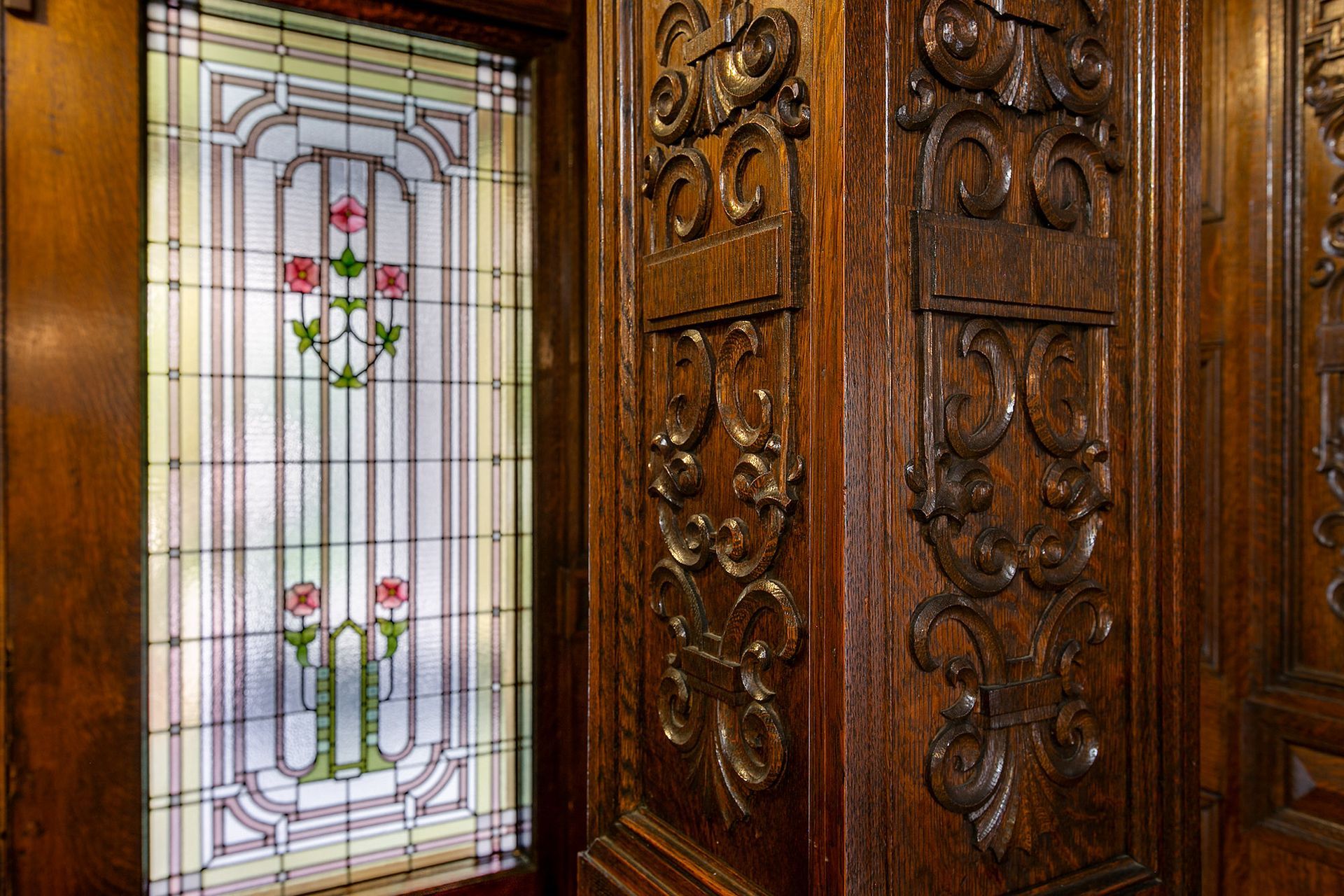 A close up of a stained glass window on a wooden wall.