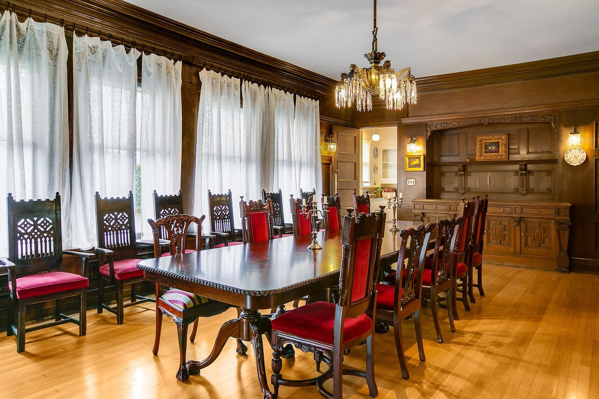A dining room with a long table and red chairs