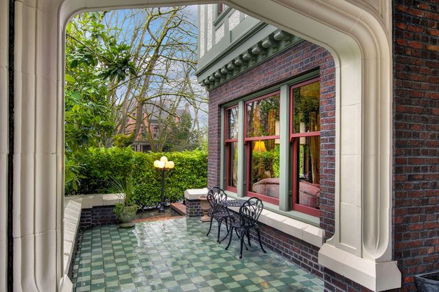 A porch with a table and chairs in front of a brick building.