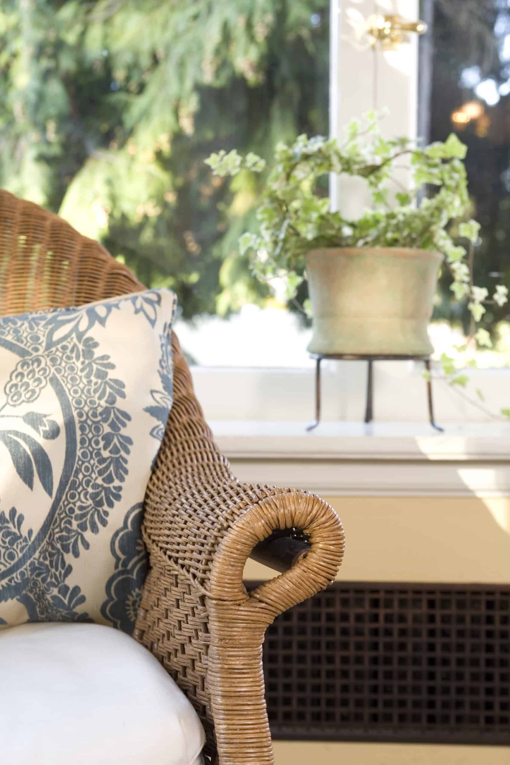 A wicker chair with a blue and white pillow on it