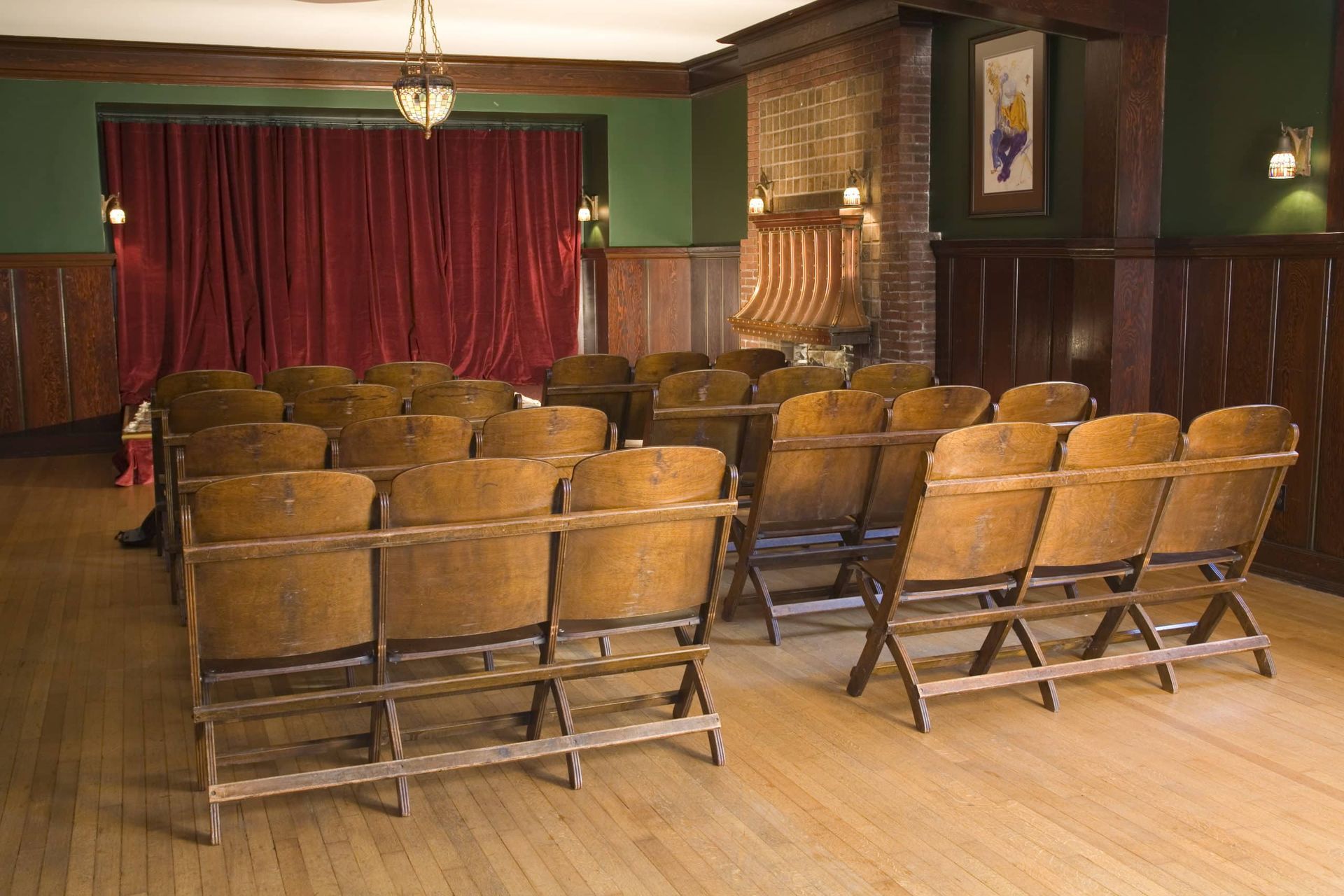 A row of wooden chairs are lined up in front of a stage.