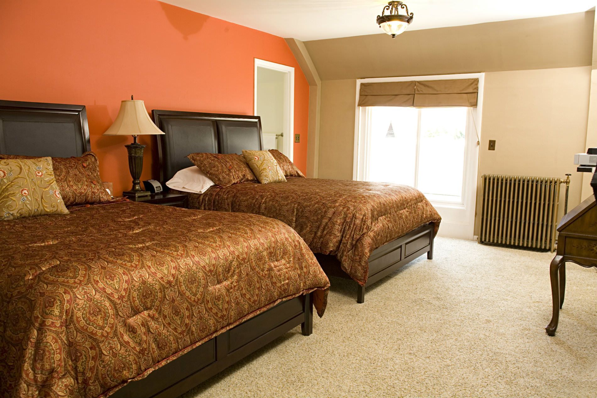 A bedroom with two beds and an orange wall