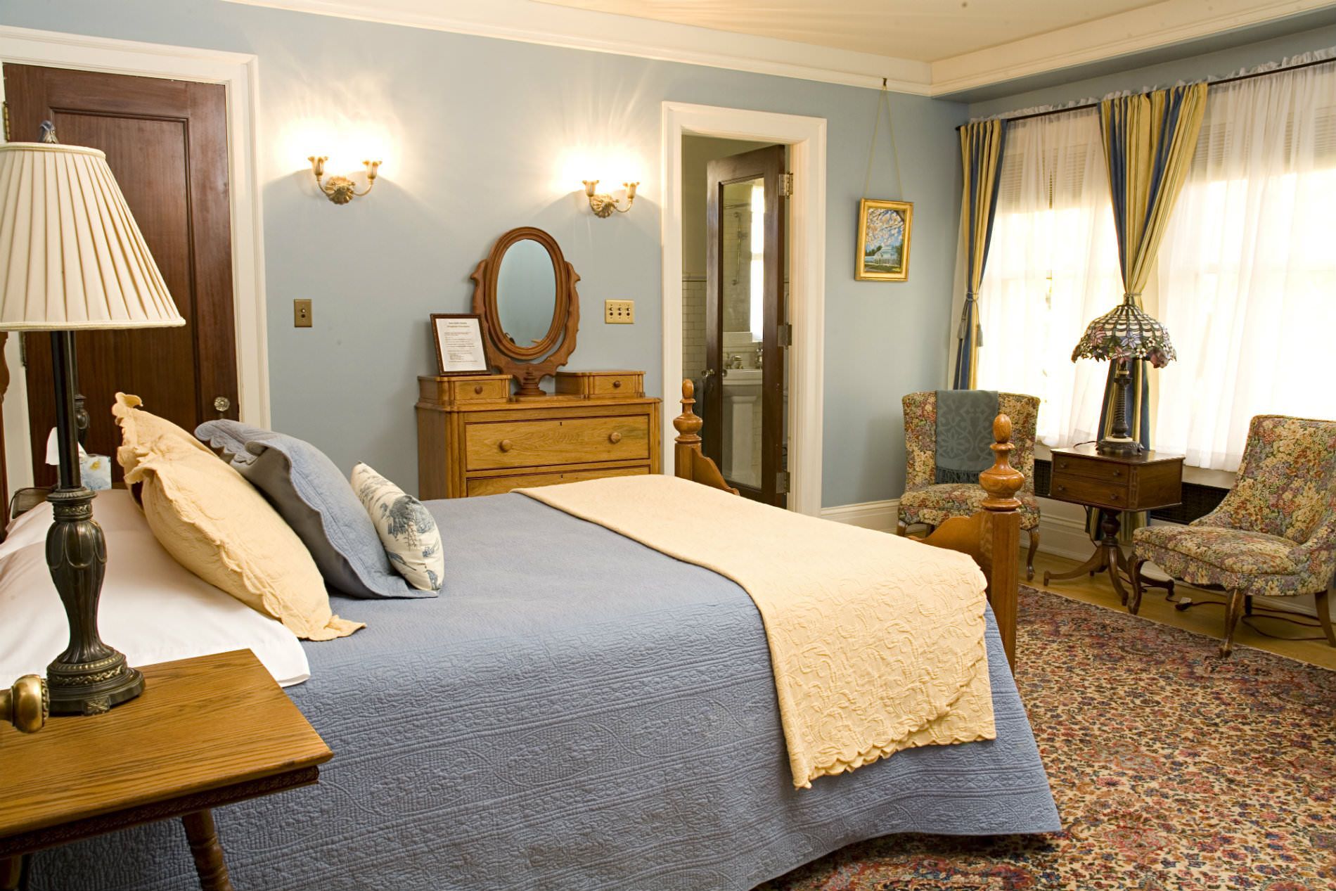 A bedroom with a large bed dresser and chairs