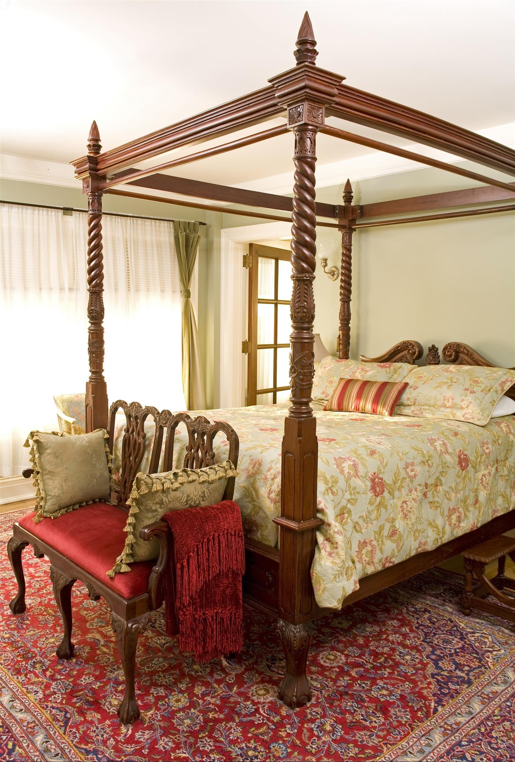 A bedroom with a canopy bed and a bench