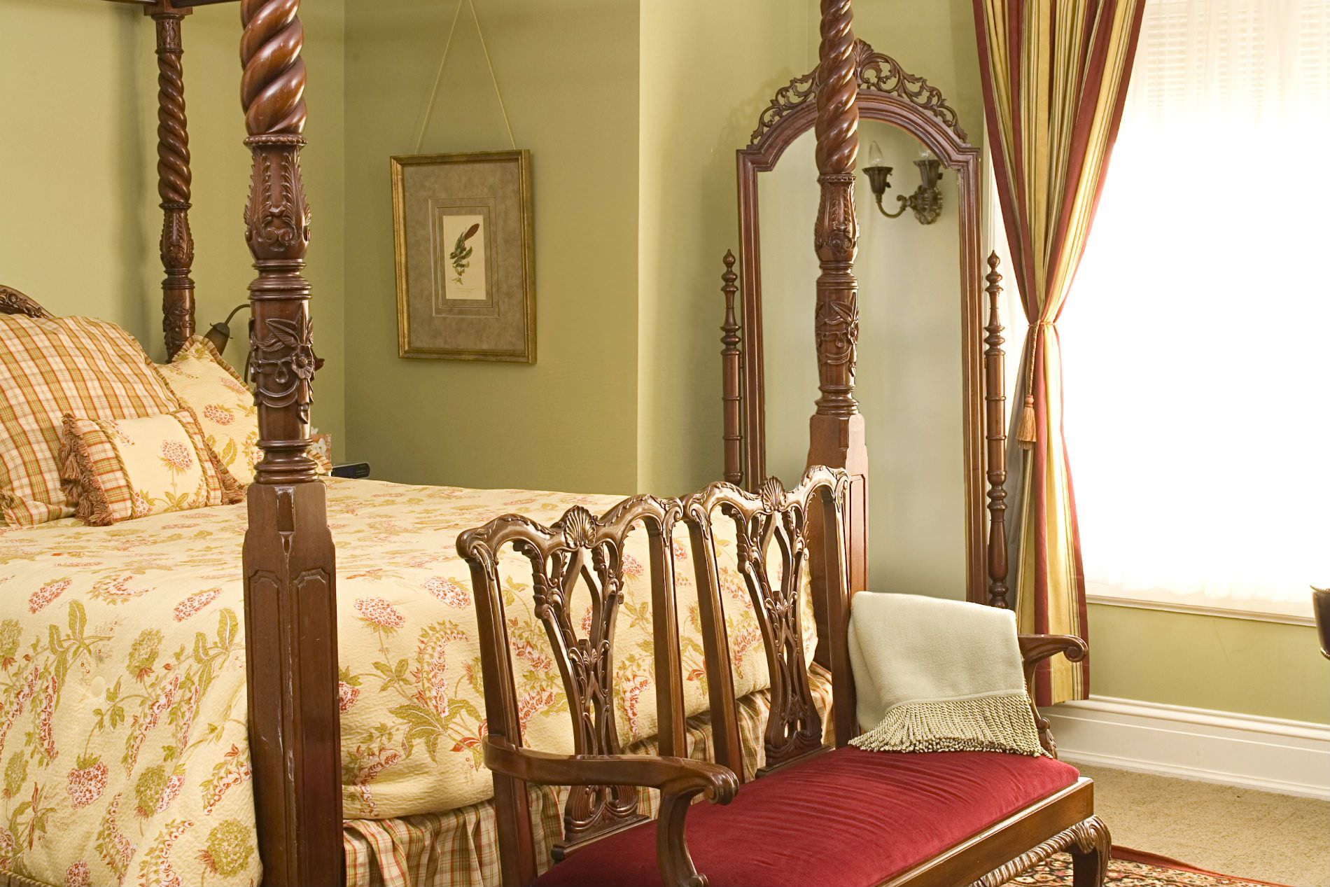 A bedroom with a four poster bed and a chair