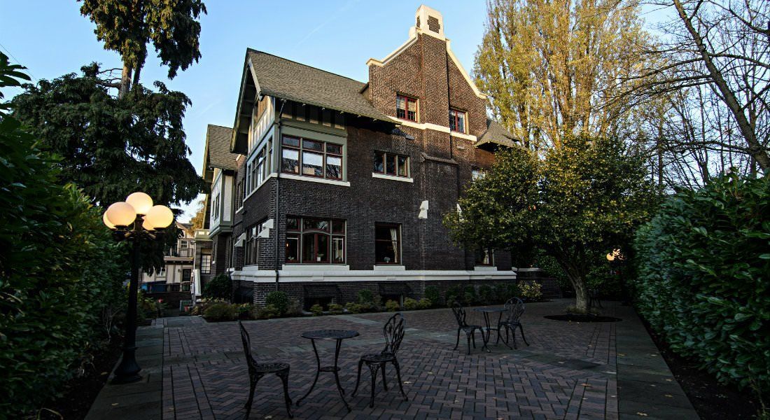 A large brick house with tables and chairs in front of it