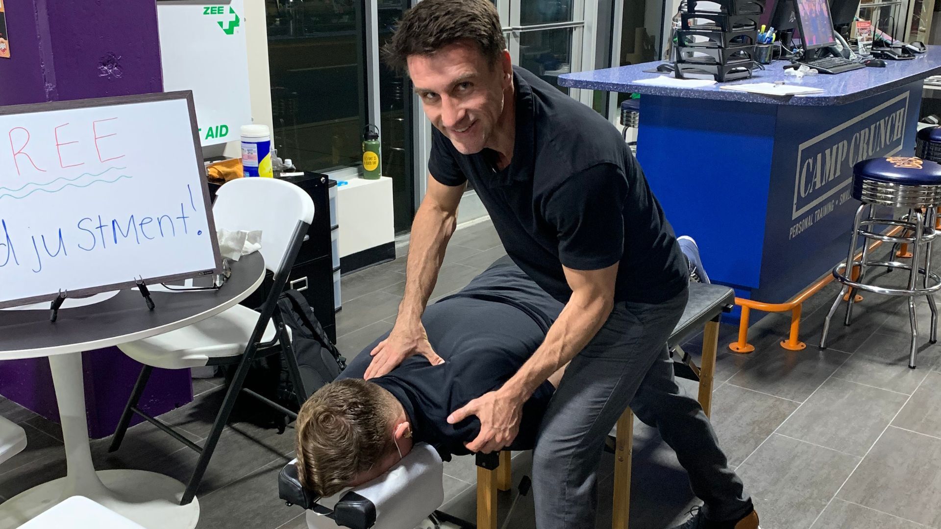 A man is giving a man a massage in a gym.