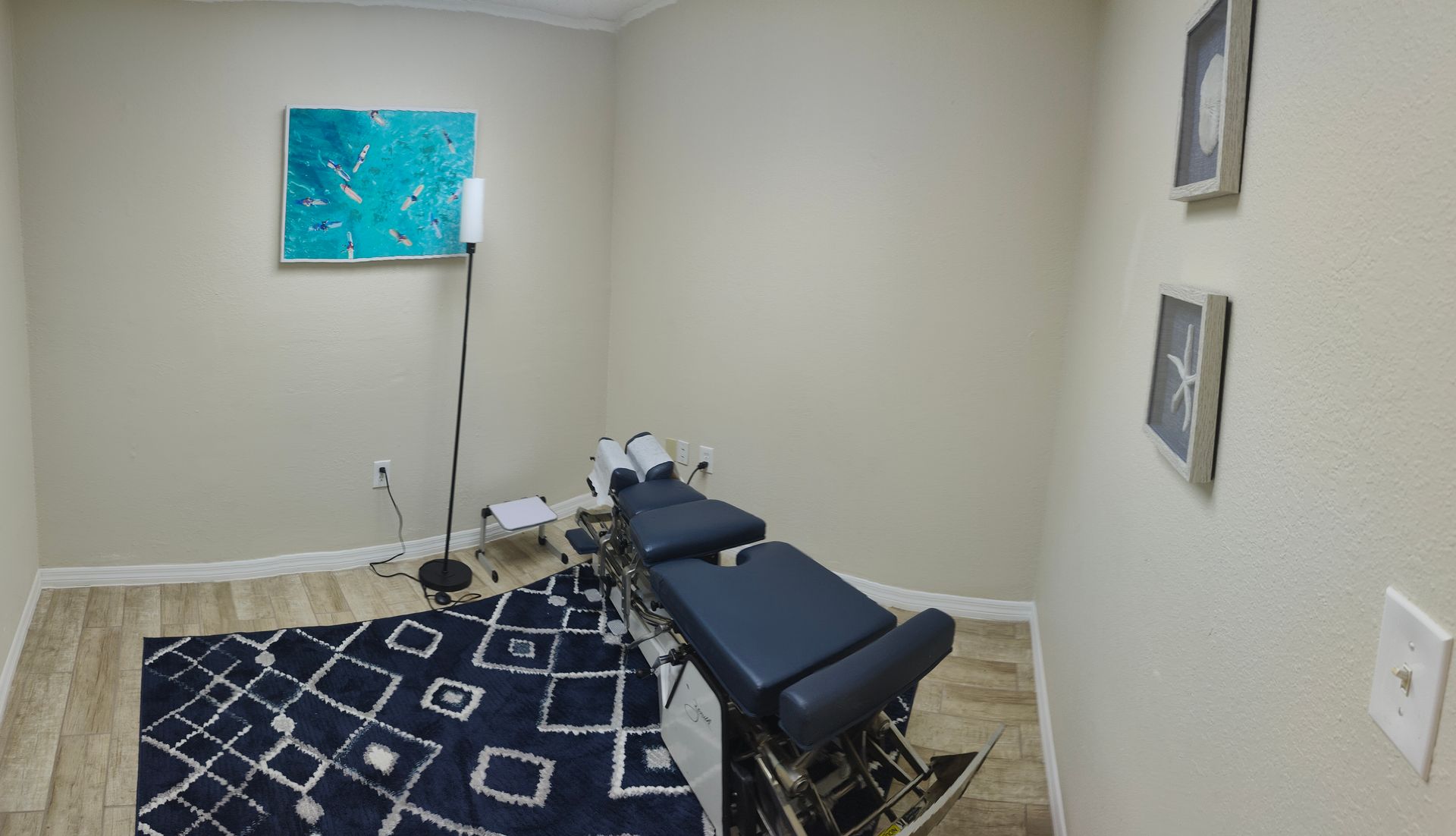 A room with a massage table and a rug on the floor.