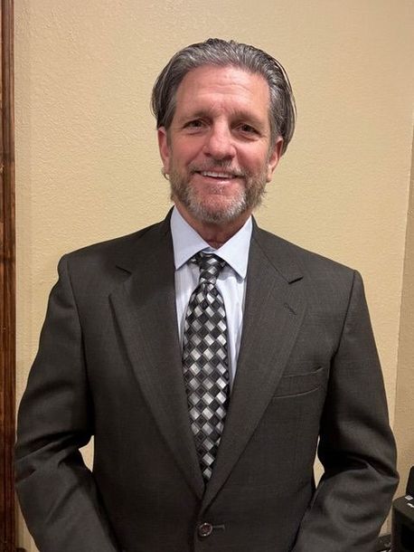 A man in a suit and tie is smiling for the camera