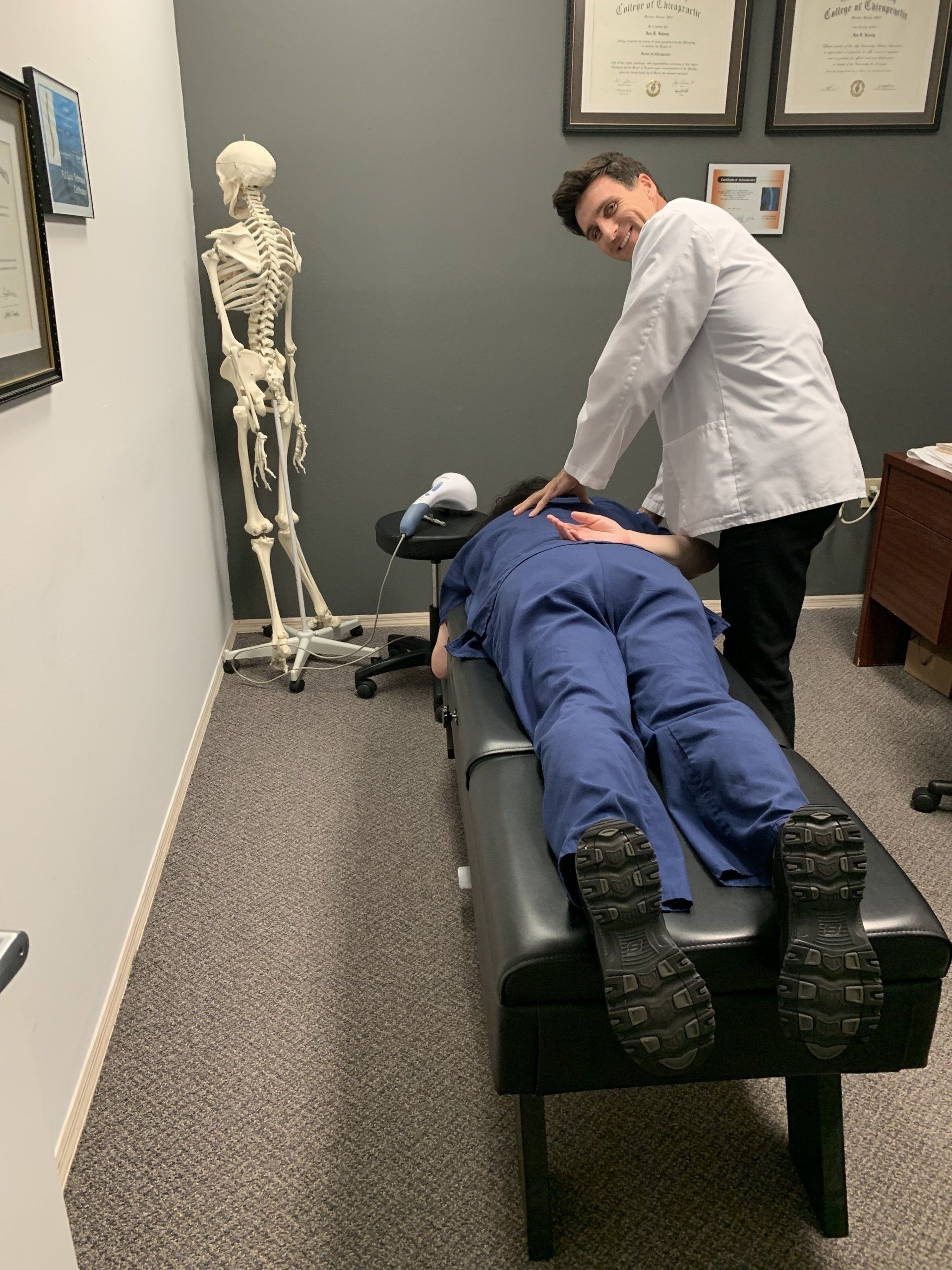 A man is giving a woman a massage in a room with a skeleton in the background.