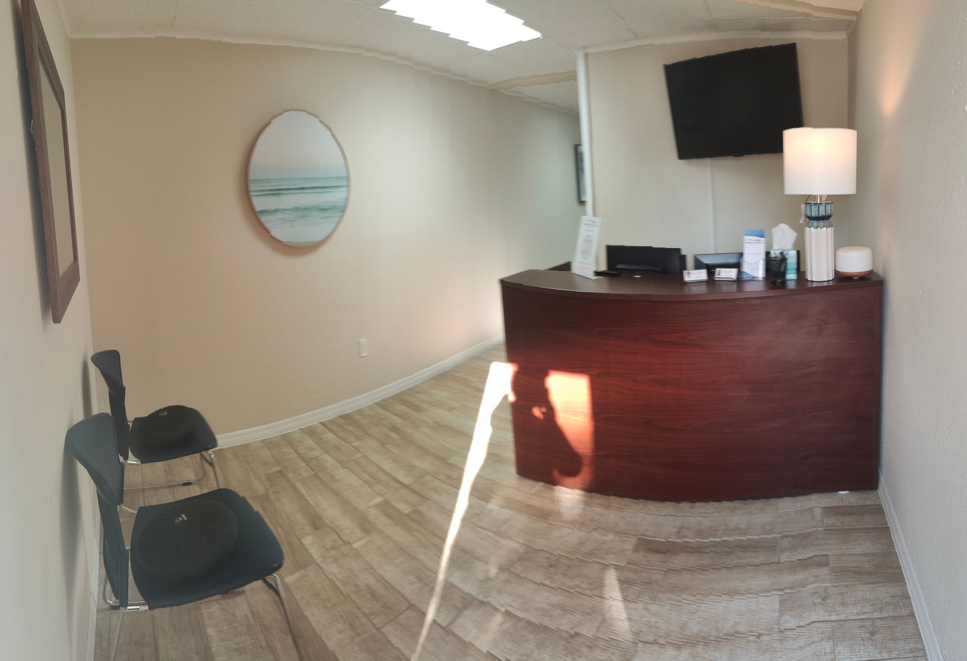 A waiting room with a desk , chairs and a television.