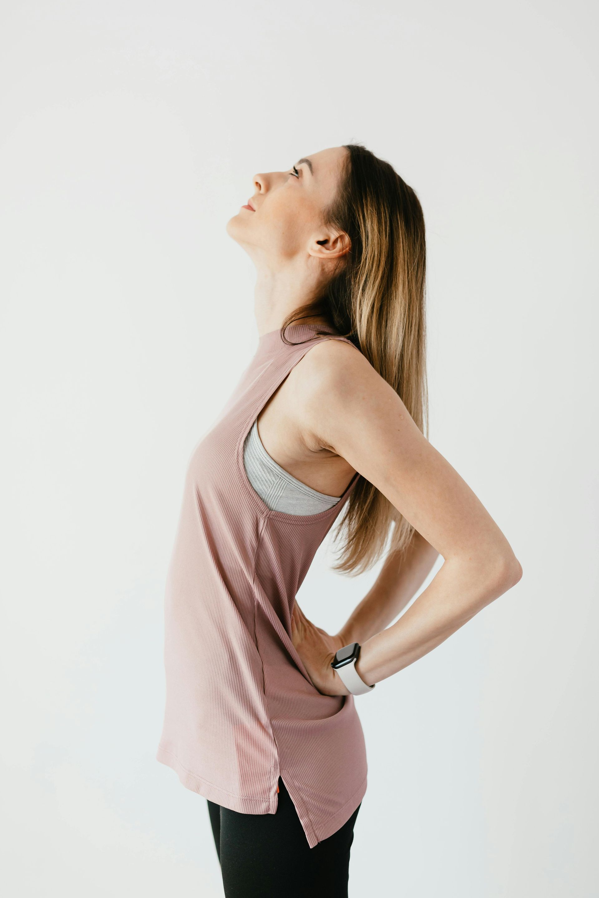 A woman stretching with her hands on her lower back.