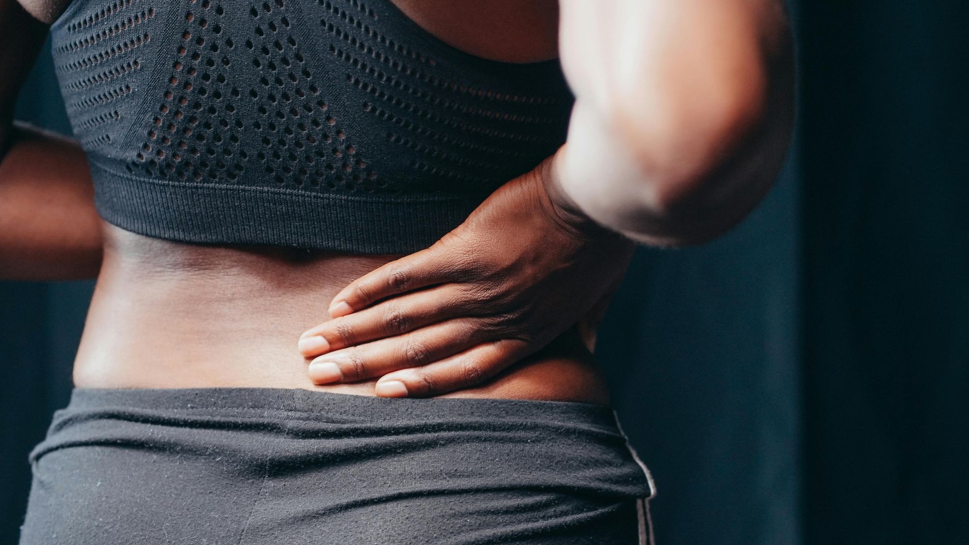 A woman placing her hand on her lower back.