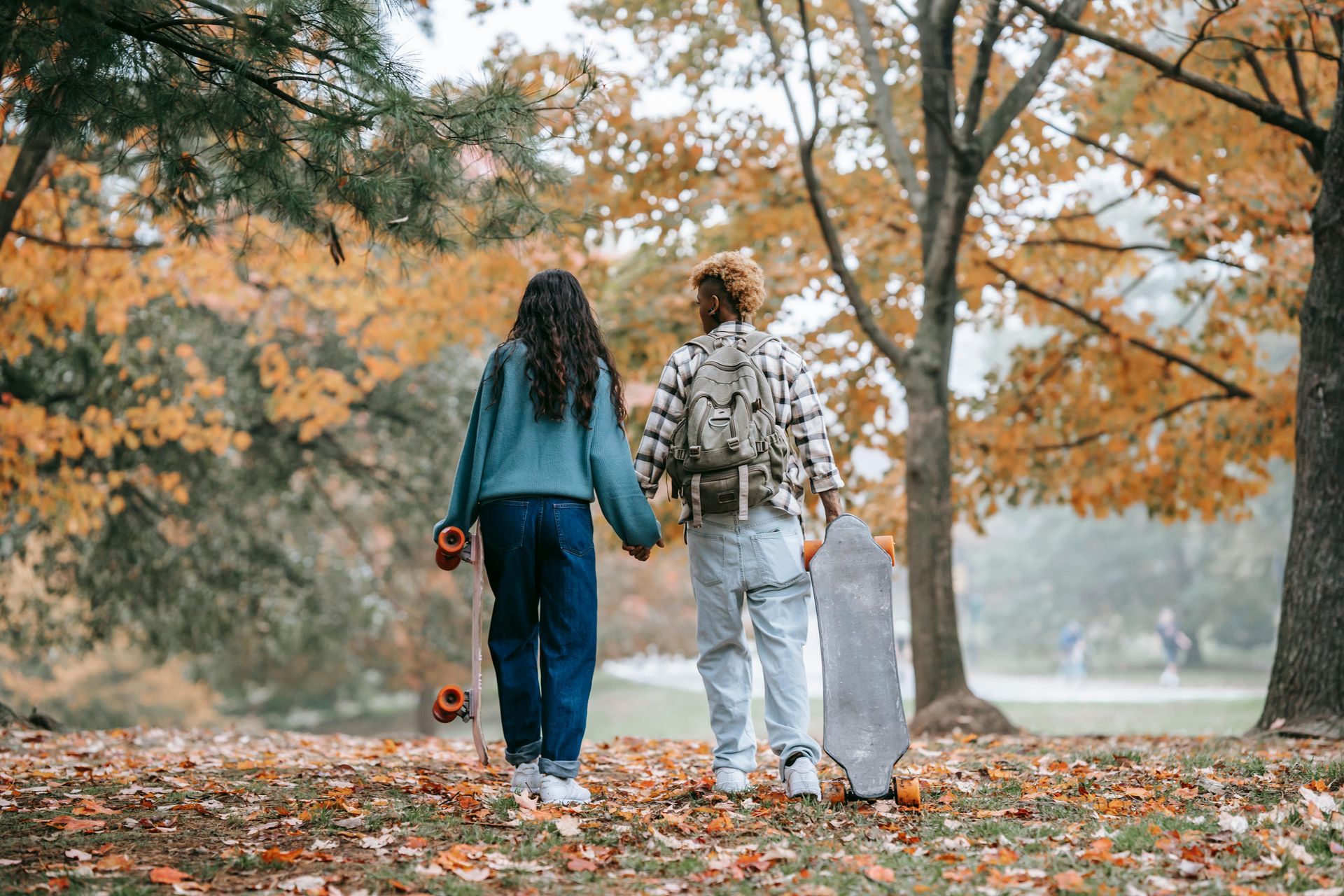 a couple walking through fall leaves
