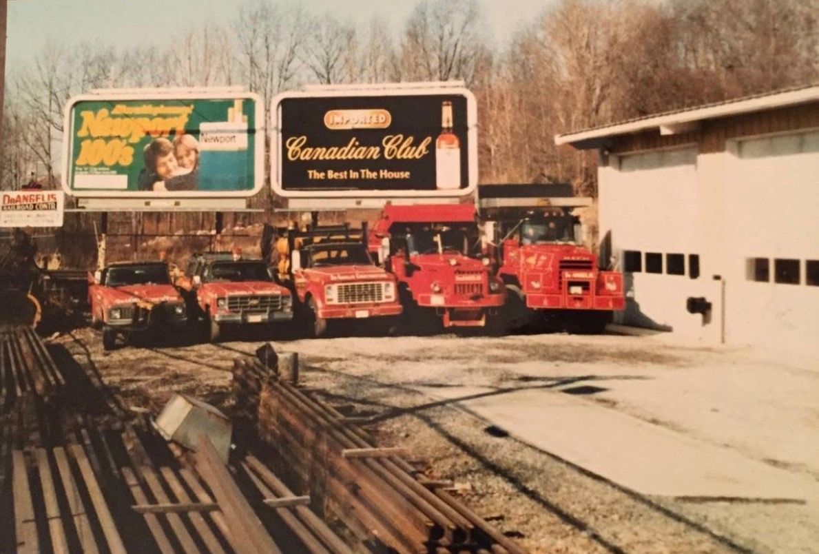 Race cars lined up on a snowy track beside billboard ads and a building