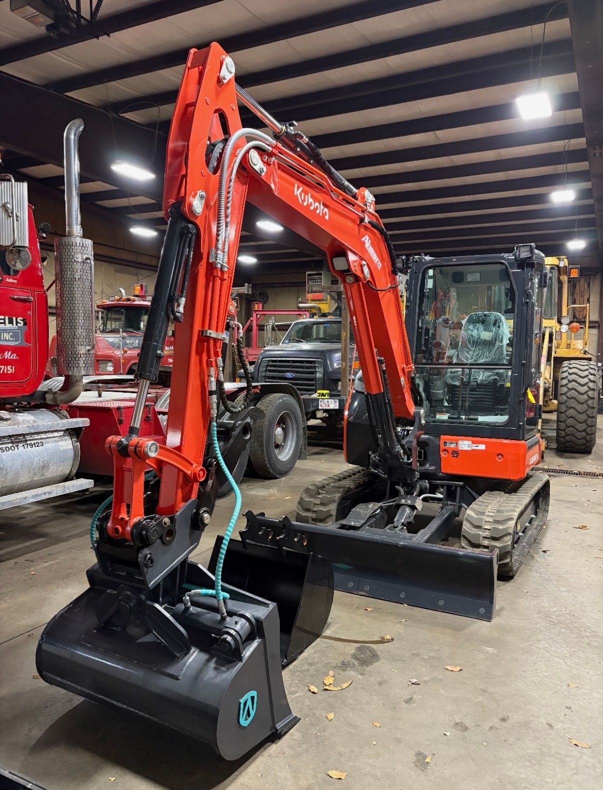Orange mini excavator with bucket in an indoor machinery showroom or warehouse