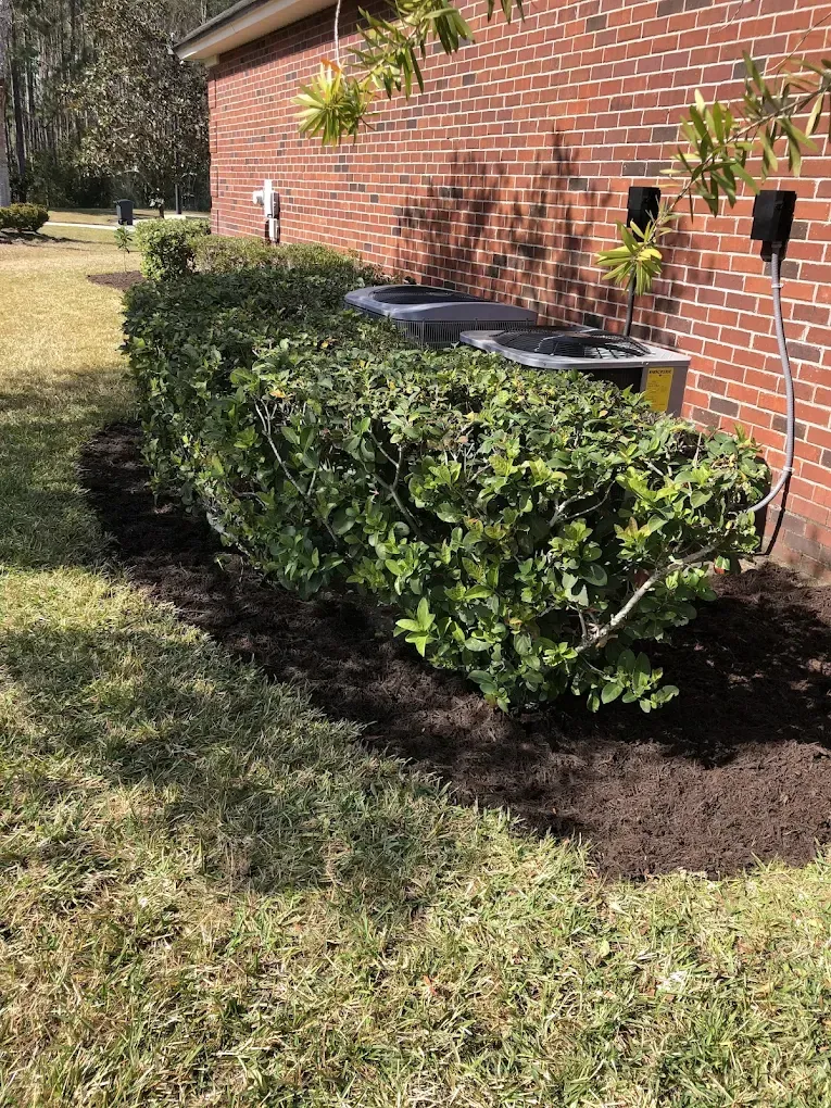A brick building with a hedge in front of it.