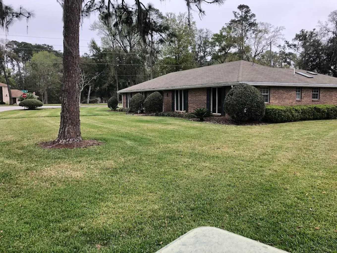 A brick house with a large lawn in front of it.
