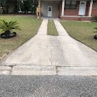 A concrete driveway leading to a brick house.