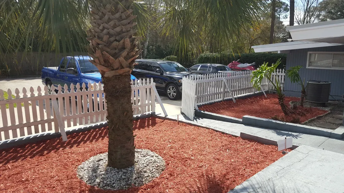 A blue truck is parked in front of a house with a white picket fence.