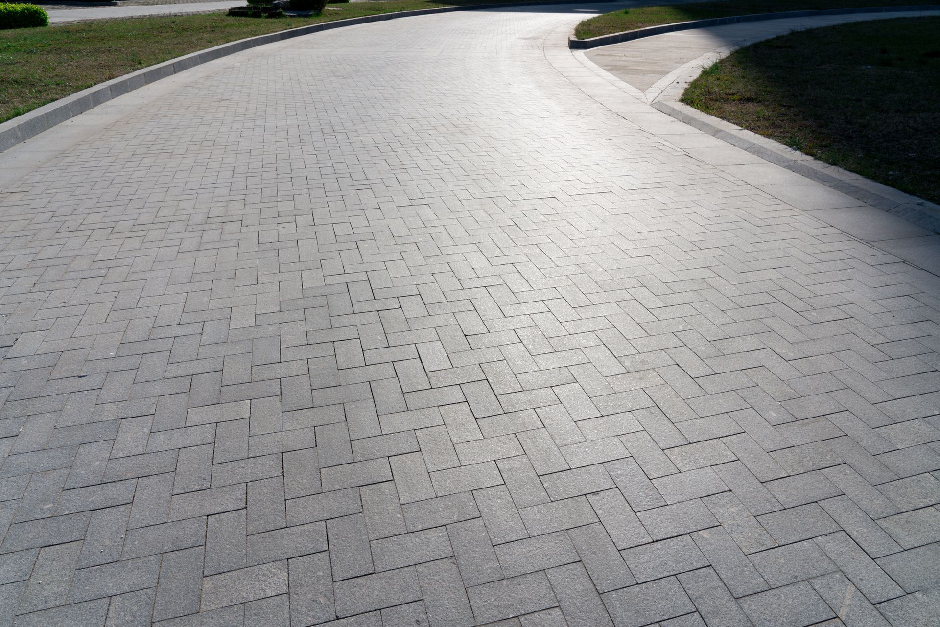 Curved paved pathway with interlocking bricks and grass on both sides. Curved paved pathway with interlocking bricks and grass on both sides.
